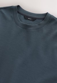 Dark teal crewneck sweatshirt made from a soft material, featuring a smooth texture and a minimalist design with no visible patterns.