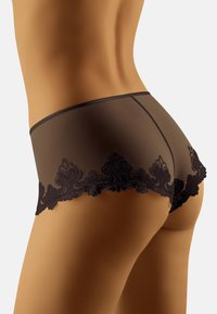 Boyshorts in pizzo nero caratterizzati da un tessuto trasparente con ricami floreali lungo l'orlo a scallop, che esaltano un design morbido e aderente.