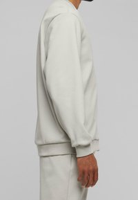 Ljusgrå sweatshirt i mjukt tyg, med rund halsringning, långa ärmar samt ribbade muddar och nederkant. Enkel, modern design.