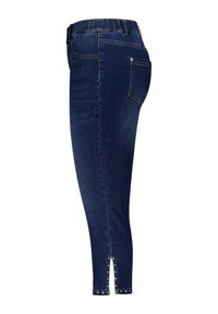 Jeans skinny en denim bleu foncé avec une taille élastique haute, présentant un design à fente sur le côté rehaussé de clous en argent au bas.