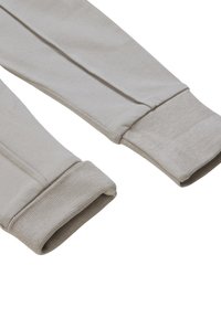 Graue Baumwollhosen mit gerippten Bündchen, die eine glatte Textur und eine taillierte Form an den Knöcheln haben. Einfaches Design ohne Muster oder Verzierungen.