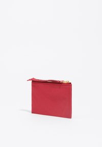 Funda plana de nylon rojo con cremallera. Presenta una cremallera dorada y una textura suave. Diseño compacto adecuado para objetos pequeños.