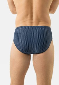 Slip de bain bleu marine avec un motif circulaire, une coupe ajustée et un tissu lisse. La vue de dos montre une finition sans coutures et un ajustement confortable.