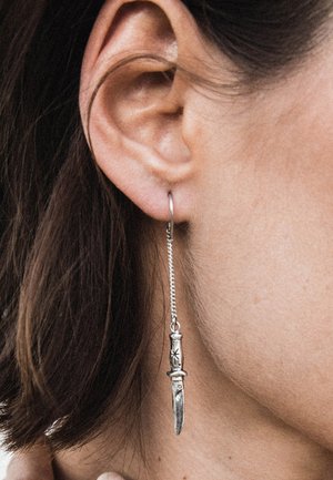Zilveren oorbel in de vorm van een mes heeft een hangend ontwerp met een ketting. Opvallende details zijn de gegraveerde handgreep en de strakke lijn van de lemmet.