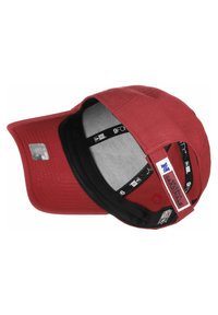 Sarkans beisbola cepure ar izliekto vizoru. Tam ir pelēka iekšpuse un melna sviedru josta. Sporta logo birka malā ar regulējamu siksnu.