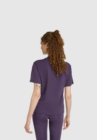 Lila Baumwoll-T-Shirt mit entspannter Passform, kurzen Ärmeln und einem schlichten Design. Die Rückansicht zeigt minimale Nähte und keine Logos.