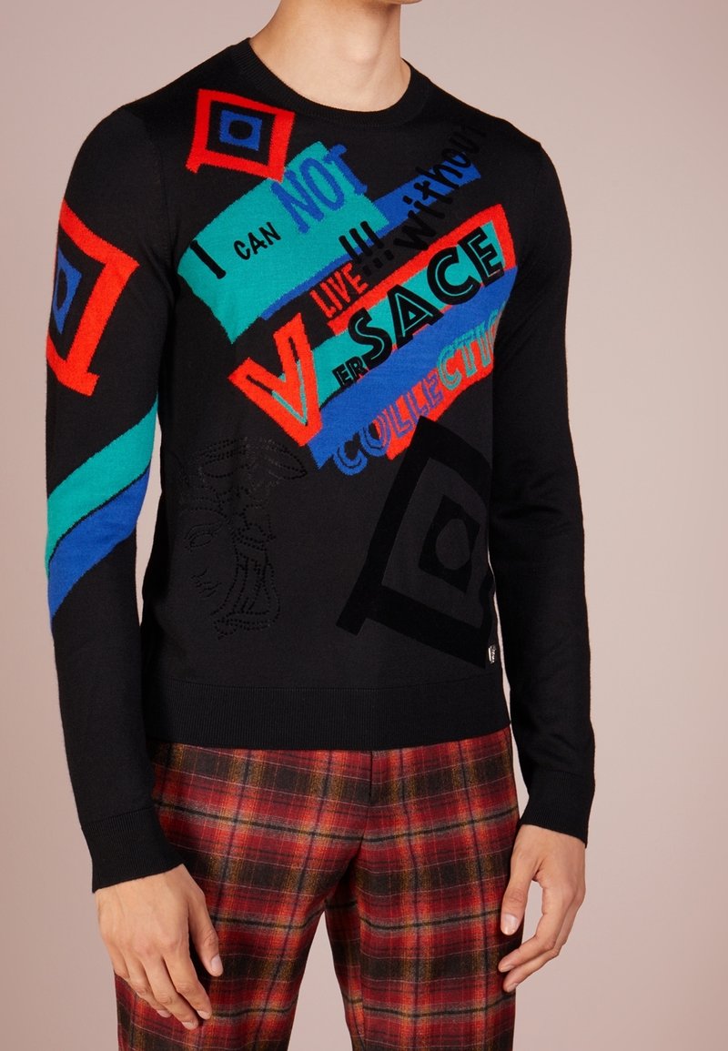Zwarte trui met gedurfde, multicoulour geometrische patronen, tekst en accenten. Gemaakt van zachte stof met een ronde halslijn en geribde manchetten.