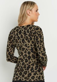 Langärmliges Oberteil in Olivgrün mit einem schwarzen Leopardenmuster, ausgestattet mit einem Rundhalsausschnitt und einer lockeren Passform. Sanfte Baumwollstofftextur.