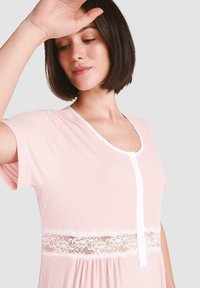 Camisón de color rosa claro con mangas cortas, cierre de botones en la parte delantera, acento de encaje en la cintura, textura acanalada y escote redondeado.