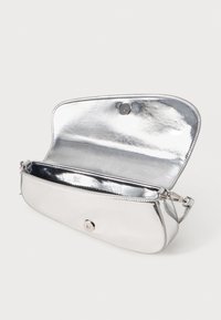 Small silver metallic shoulder bag with open flap and magnetic snap closure, showing empty interior and adjustable strap buckle.