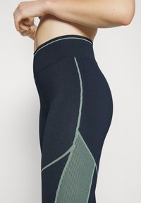 Leggings blu navy in un design fitted con accenti verdi testurizzati e cuciture verticali, dotati di una cintura larga per il massimo comfort.