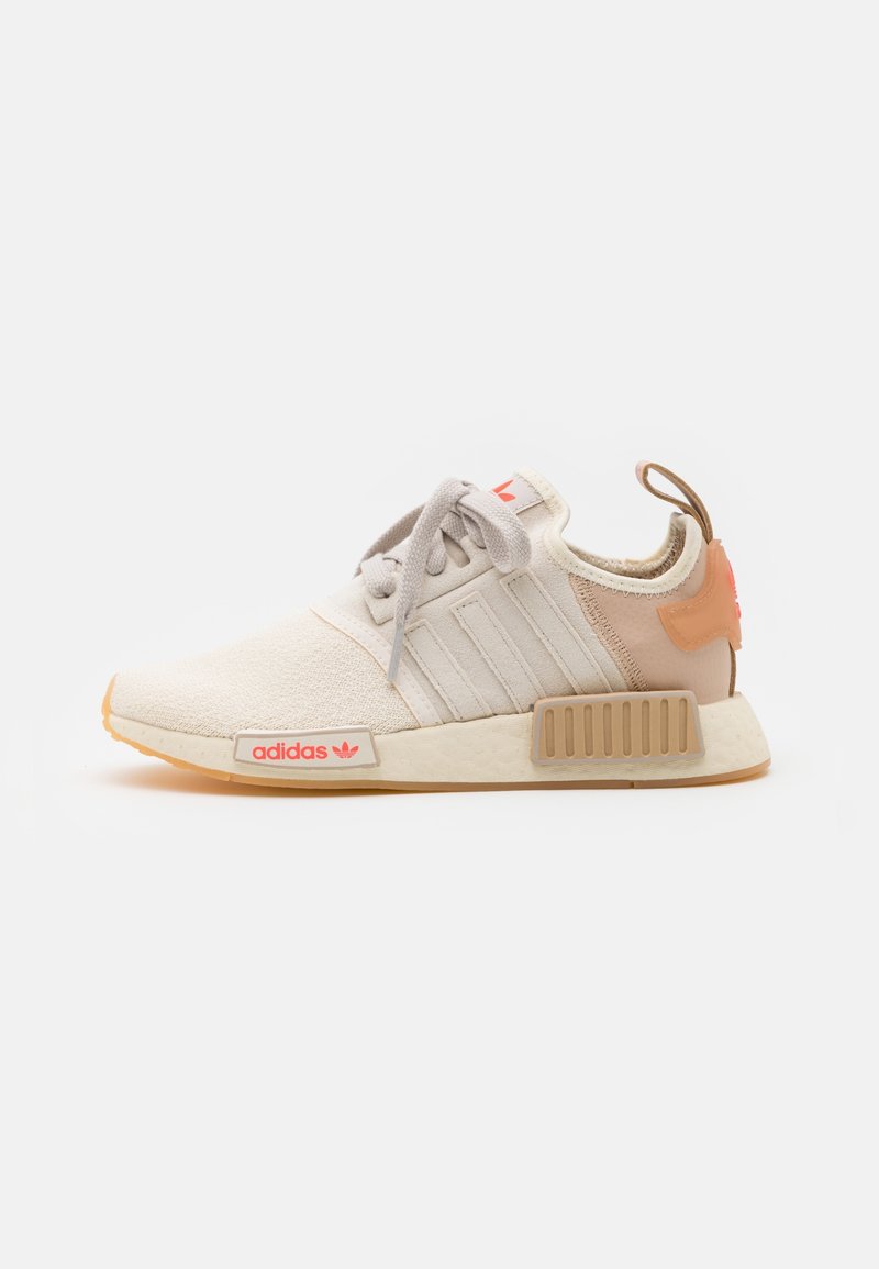 Tenisky Adidas NMD v světle béžové textilu s třemi bočními pruhy, gumovou podrážkou a růžovými akcenty na patě a logu.