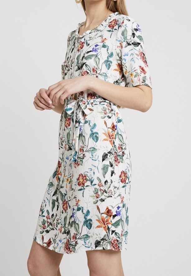 Vestido con estampado floral en tejido ligero, que presenta mangas cortas, una cintura ceñida con cinturón y un escote redondo. Los colores incluyen verde, rojo y azul.