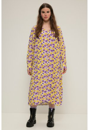 Robe longue à motifs floraux jaunes et violets avec un devant boutonné, des manches longues et une coupe décontractée, associé à des bottes noires chunky.