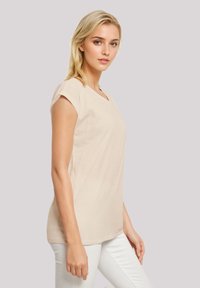 Beige T-Shirt mit kurzen Ärmeln im lässigen Schnitt und rundem Ausschnitt, aus weichem Baumwollmaterial hergestellt. Verfügt über eine glatte Textur und ein einfaches Design.