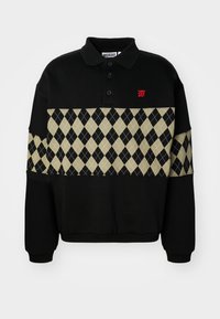 Sweat-shirt noir à col montant, avec une bande en losanges beige à motif et un petit logo rouge sur la poitrine.