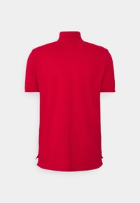 Rød polo shirt lavet af blød bomuld med krave og korte ærmer. Har sideslids ved kanten for en afslappet pasform.