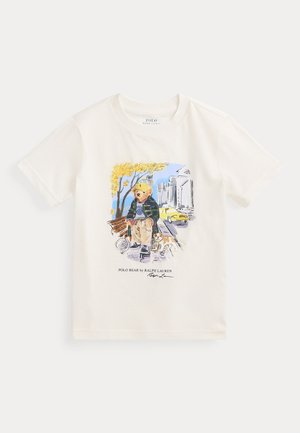 T-shirt en coton crème à manches courtes présentant une illustration colorée d'un ours en hoodie avec un chien, sur fond urbain.