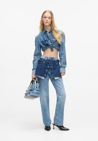 Σαλοπέτα τζήν με κόμπο και φορεματίτσα με στρώσεις: ανοιχτό μπλε αποχρώσεις, λεπτομέρειες με κουμπιά, με τζιν κατευθείαν πόδια και τακούνια με μακρύ μπροστινό.