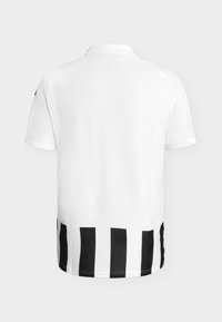 Chemise blanche à manches courtes vue de dos, avec des rayures noires verticales le long de l’ourlet inférieur. Aucun logo ni texte visible.