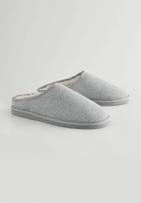 Szare materiałowe kapcie z textured powierzchnią, miękkim wewnętrznym wykończeniem i zaokrąglonym noskiem. Styl slip-on z kontrastowym wykończeniem i płaską podeszwą.