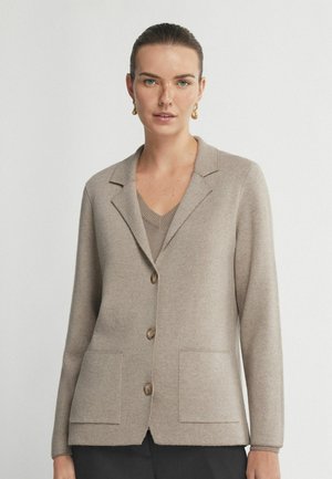 Beige stickad cardigan med notchad krage, tre knappar, två framfickor, långa ärmar och en slät textur.
