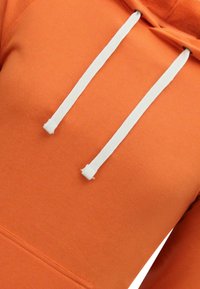 Oranje hoodie gemaakt van een katoenmix, met een kenguruzak, witte trekkoorden en een zachte, gestructureerde stofafwerking.