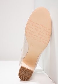 Scarpa in suede beige con suola in gomma testurizzata. Presenta un marchio impresso sulla suola e la taglia "37" indicata.