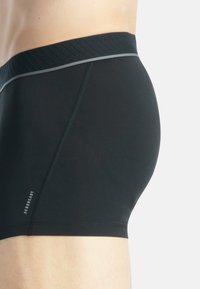 Svarta boxertrosor med en strukturerad midja, grå accent, slät tygkvalitet och åtsittande form, designade för komfort och stöd.