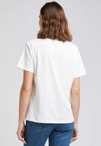 T-shirt en coton blanc à manches courtes, présentant une coupe décontractée. La vue arrière montre un design simple sans logos ni motifs visibles.