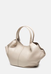 Borsa tote in pelle beige con due lunghe manici, forma leggermente arrotondata, superficie testurizzata e design minimalista. Nessun hardware o accenti visibili.