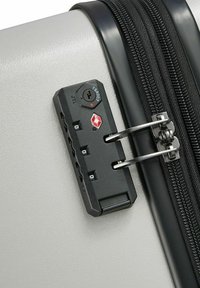 Grijze kofferhoek met een zwart TSA-slot, rits en combinatiedial. Glad afwerkingsmateriaal, stevige ritsen en details van het veilige vergrendelmechanisme.