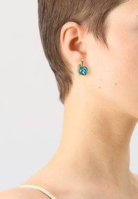 Cercei aurii cu o piatră cuadrată din turcoaz cu fațete, care prezintă un design elegant și un sistem de prindere sigur cu spate.