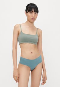 BH und Bikini-Set in sanftem Olivgrün und tealblau. Der BH hat dünne Träger; der Bikini hat ein glattes, nahtloses Design.