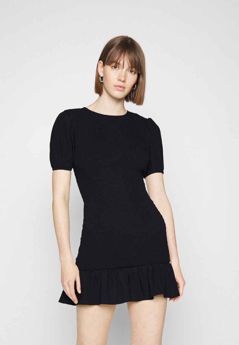 Vestido preto curto com mangas bufantes, textura plissada e barra em godê. Tecido suave; silhueta ajustada que afunila na cintura.