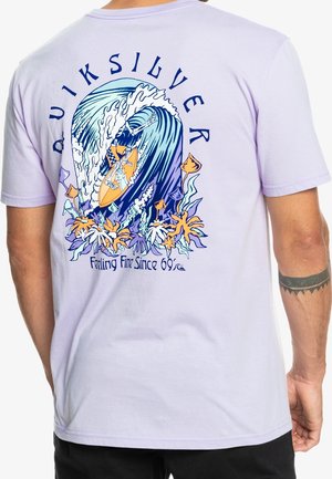 Lilak bomulds T-shirt med et farverigt bølge- og surfbræt grafik på ryggen, med blomsteraccentuer og teksten "Feeling Fine Since 69."