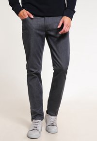 Grå denimbyxor med slim fit, med en jämn yta och rena linjer, parat med ljusgrå sneakers.