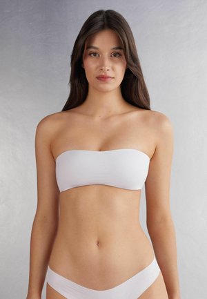 Vit sömlös bandeau-topp med en slät textur och enkel design, i kombination med matchande lågmidjade trosor.
