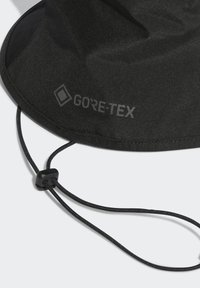 Melnā šūpuļcepure, kas izgatavota no Gore-Tex materiāla, ar zoda siksnu ar regulējamu uzgali un apdrukātu logotipu. Strukturēta virsmas apdare.