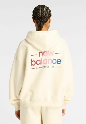 Felpa color crema con cappuccio, caratterizzata da un grande logo "new balance" multicolore sulla schiena, con una vestibilità rilassata e una texture morbida.