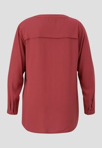 Bluza dugih rukava u boji hrđe izrađena od glatkog materijala. Ima yoke detalj na leđima i rukave sa dugmadi.