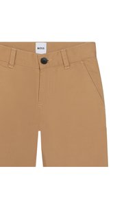 Beige byxor med standardpassform, framfickor och knappstängning. Kontrasterande sömmar framhäver designen.
