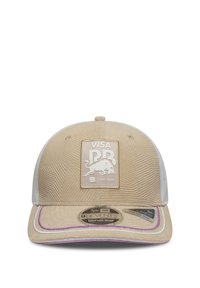 Beżowa czapka z teksturowanej tkaniny, biała siateczkowa tył, fioletowe akcenty z przyszytymi nićmi oraz kwadratowa naszywka z logo przedstawiająca byka i tekst.
