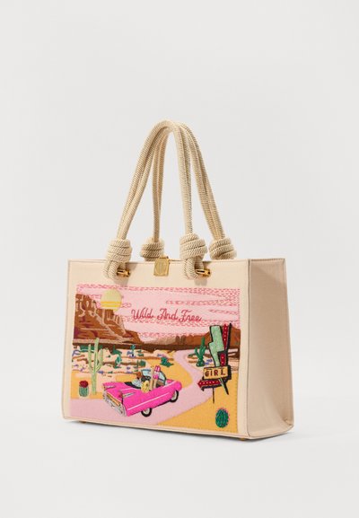 Beige tote bag with rope handles, featuring colorful embroidered desert scene, convertible car, cacti, and text “Wild And Free.”
