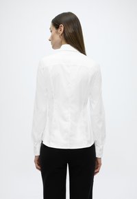 Λευκό εφαρμ οστό πουκάμισο με μακριά μανίκια, λεία υφή και μανσέτες με κουμπιά, με πίσω γιάκα και κομψή γραμμή.