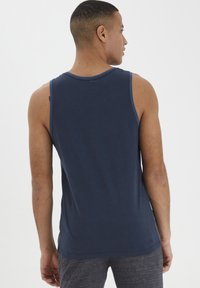 Marineblå ærmeløs tanktop, lavet af blødt stof, med en rund halsudskæring og en ren finish. Bagfra viser en enkel design.