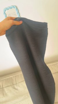 Rudai tekstūra tamsios medžiagos, laikomos žmogaus rankoje, su šviesiai mėlynu, pintu rankena viršuje, nurodančia funkcionalų dizainą.
