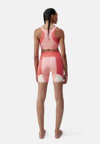 Athletic set in gradient pink hues, featuring a fitted sports bra with wide straps and high-waisted shorts with contrasting white accents.