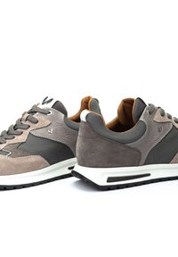 Zapatillas de hombre con ante y malla gris, lengüeta acolchada, detalles reflectantes y una media suela blanca con suela negra.