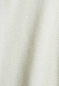 Gros plan d'un tissu blanc tricoté montrant son motif texturé et son tissage doux.